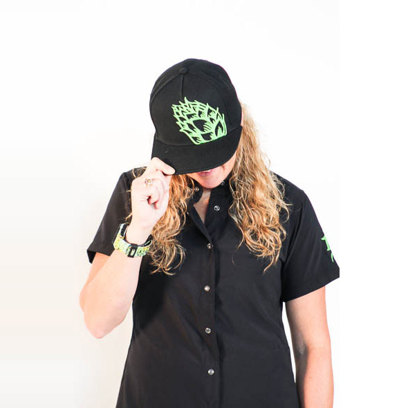Female modeling black hat with green embroidered hop logo.