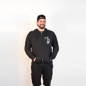 Male modeling Charcoal grey zip hoodie with pockets and heady topper logo on front left chest. Front view.