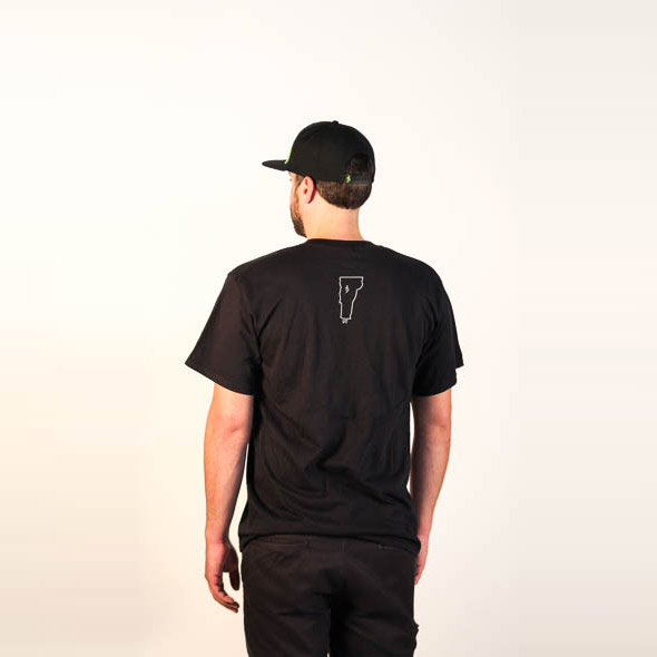 Male modeling Black tee State of Vermont and small Alchemist symbol design. Back view