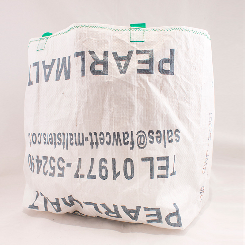 White tote bag made from malt bag. Tote has blue lettering, green strap.